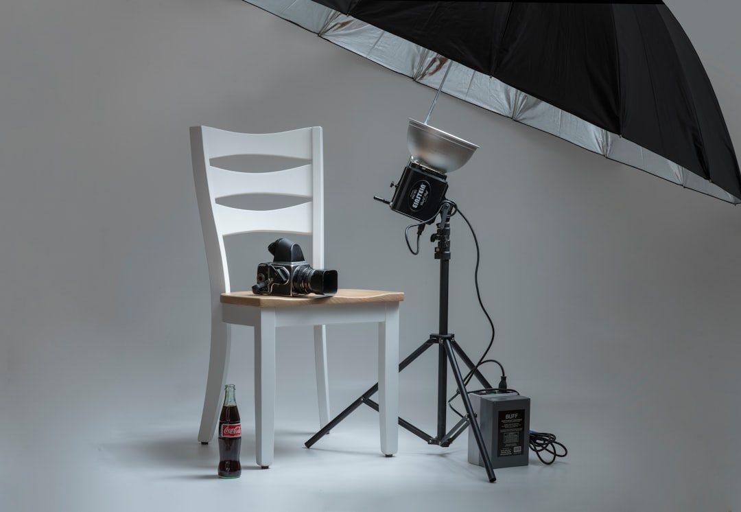 black-video-camera-on-white-wooden-chairs-beside-photo-shooting-umbrella-6iqca9-q-qq